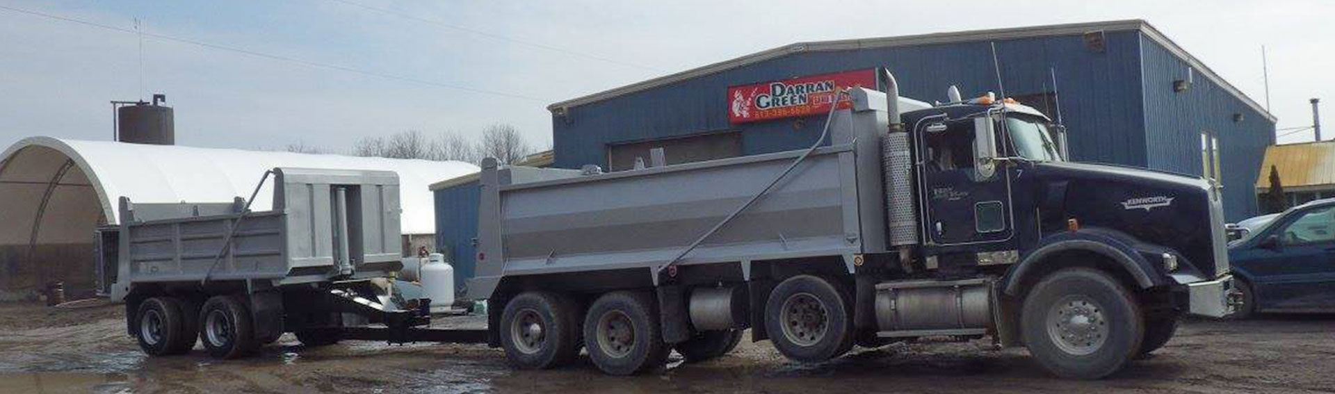 heavy equipment with trailer parked in front of Darran Green's shop